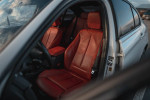 Interior of a 2013 BMW 328i showing luxurious red leather seats and modern design features.