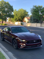 2018 Ford Mustang EcoBoost RWD in maroon color parked on street, showcasing sleek design and excellent condition.
