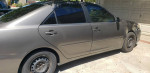 2005 Toyota Camry with low mileage, minor cosmetic dent, parked in driveway.