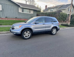 2011 Honda CR-V EX-L SUV in blue metallic parked on the street with a house in the background
