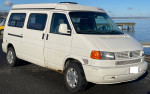 1999 Volkswagen EuroVan Camper parked by the water, featuring a white exterior and unique Winnebago design.