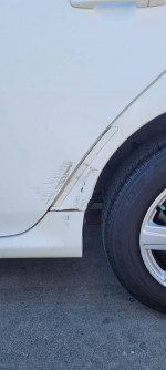 Close-up of a 2010 Toyota Corolla LE FWD showing minor scratches and a tire on a concrete surface.