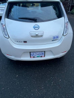 Back view of a white 2017 Nissan Leaf S electric vehicle parked on the street.