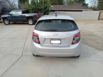 Rear view of a 2012 Chevrolet Sonic LT in silver parked on a driveway, showcasing clean and well-maintained features.