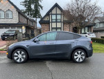 2023 Tesla Model Y Long Range all-wheel drive parked in front of a house, showcasing its sleek design