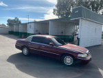 Maroon Lincoln Towncar parked at a car wash, showcasing its clean exterior and ready for test drives.