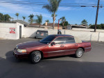 Red Lincoln Towncar with 147,000 miles parked in a lot, offering reliable transportation with clean title and functional features.