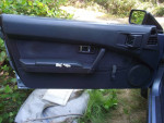 Interior door panel of a 1987 Nissan Pulsar NX, showing wear and mechanical features.