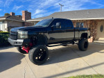 2007 Chevrolet Silverado 1500 4x4 with custom upgrades and lifted suspension parked outside a house.
