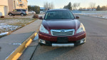 Front view of a 2012 Subaru Outback in good condition parked on a snowy street.