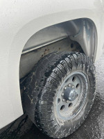 Close-up of the tire and wheel of a 2007 GMC Sierra 2500HD, showing tread and detail in wet conditions.