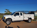 2006 Ford F250 4x4 Turbo Diesel utility truck, well-maintained with custom rims and new tires, parked outdoors.
